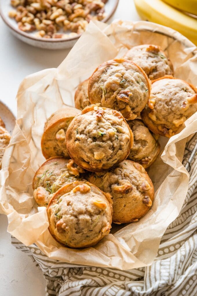 Basket full of banana zucchini muffins with walnuts.