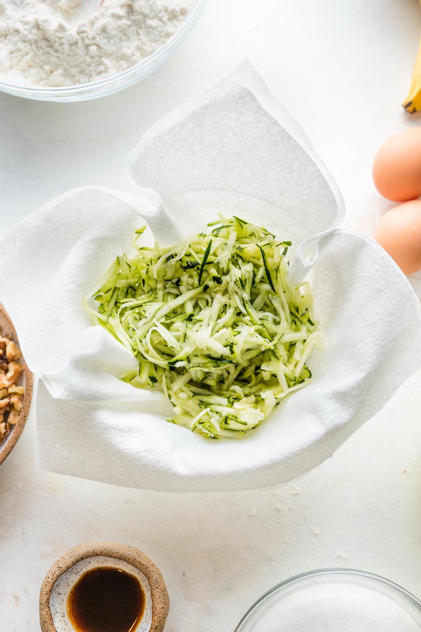 Shredded zucchini placed in a paper towel-lined bowl to dry slightly.