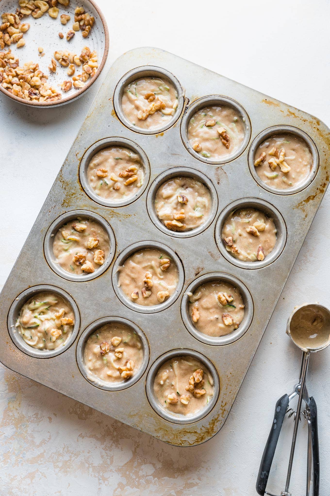 Muffin batter divided among muffin tin wells, filled almost to the top.