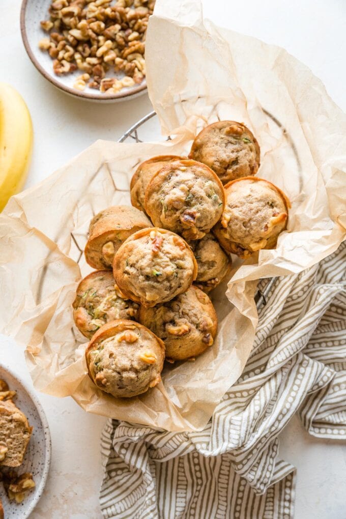 Basket full of banana zucchini muffins with walnuts.