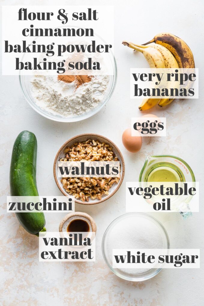 Labeled photo with flour, salt, cinnamon, baking powder, baking soda, bananas, eggs, oil, walnuts, zucchini, vanilla, and sugar in prep bowls.