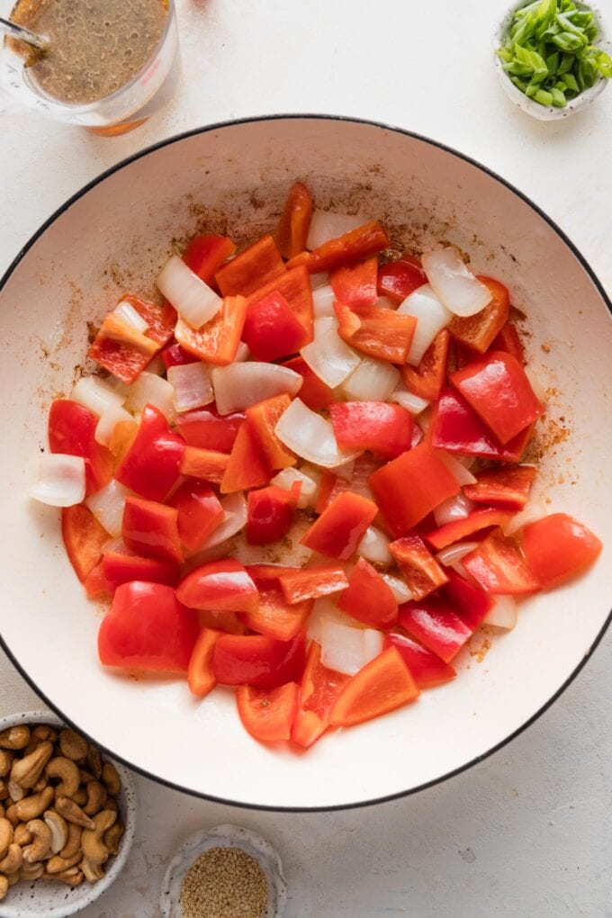Chunks of onion and red bell pepper in a skillet.