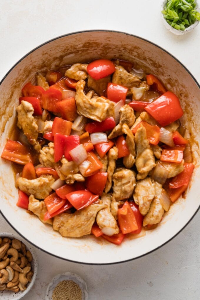 Chicken and bell peppers with stir fry sauce in a skillet.