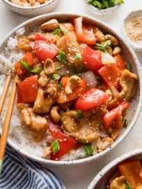 Chicken and bell pepper stir fry served in a low noodle bowl with rice.
