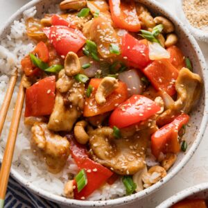 Chicken and bell pepper stir fry served in a low noodle bowl with rice.