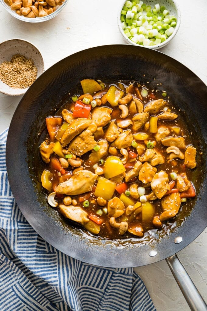 Overhead image of a wok with a simple chicken stir fry, with small garnish bowls all around.