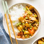 Bowl filled with rice and a stir fry with chicken, bell peppers, and cashews.