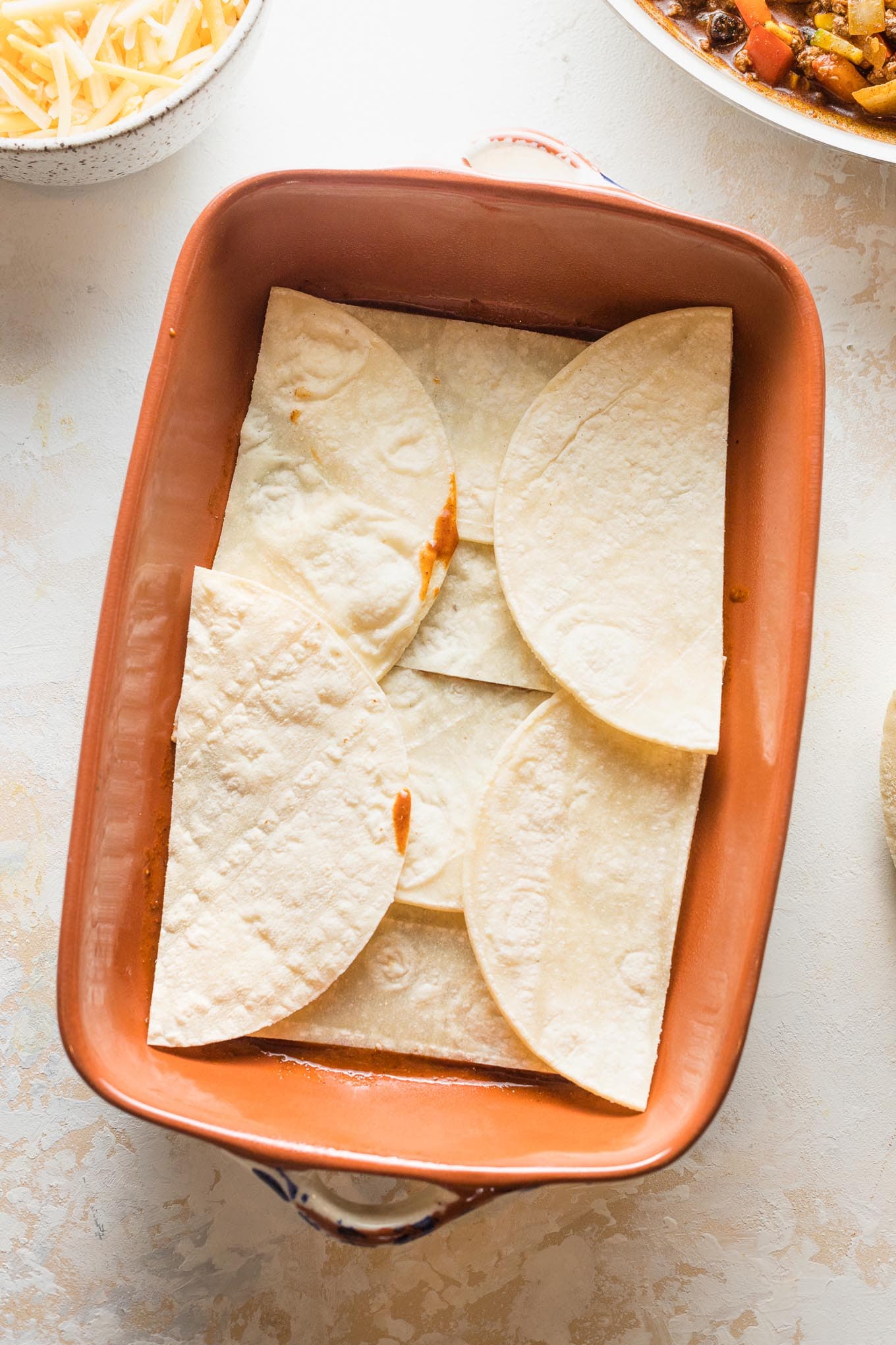 Tortillas cut in half and arranged to cover a baking pan.