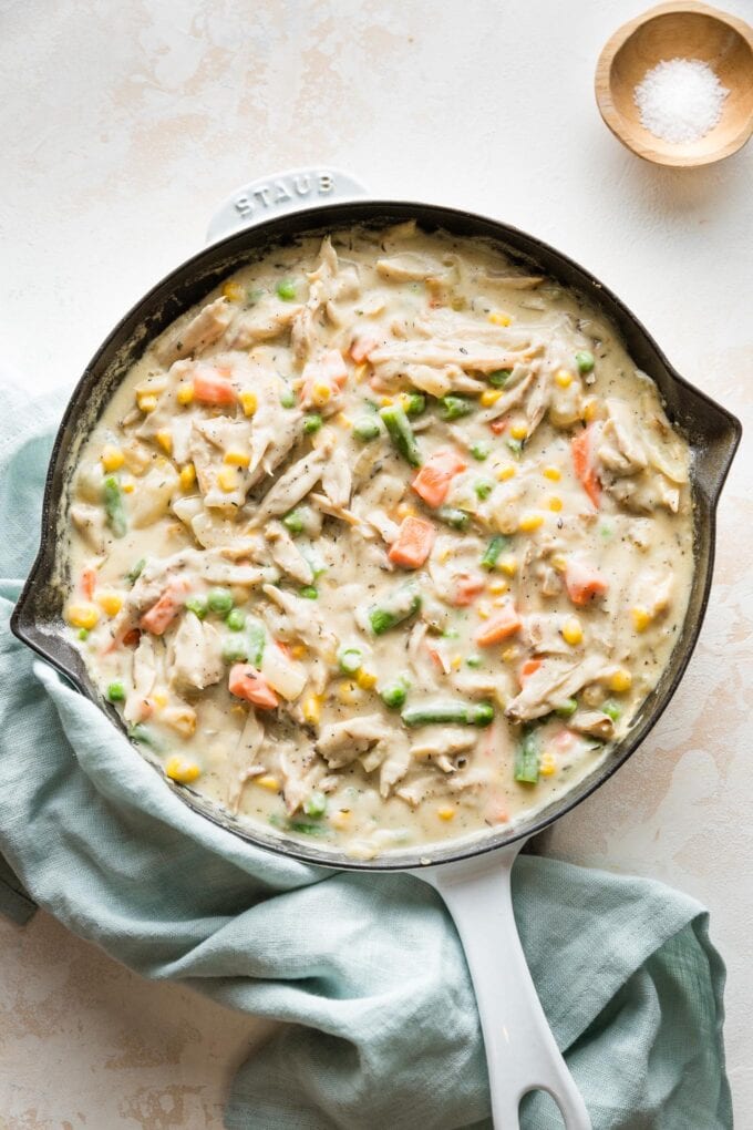 Enameled cast iron skillet holding the filling for a turkey pot pie with mixed vegetables.