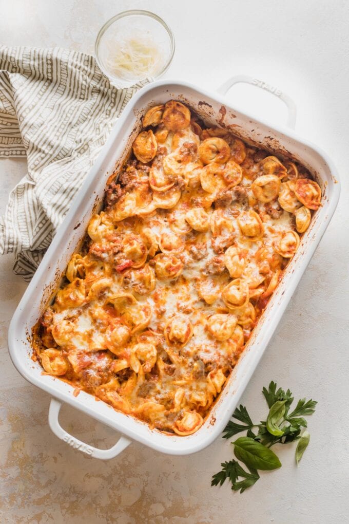 Casserole dish full of baked tortellini with meat sauce.