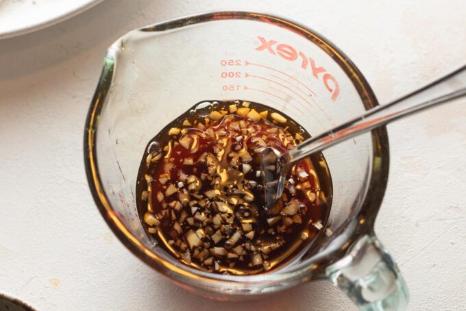 A simple glaze of honey, soy sauce, apple cider vinegar, and garlic, stirred together in a small liquid measuring cup.
