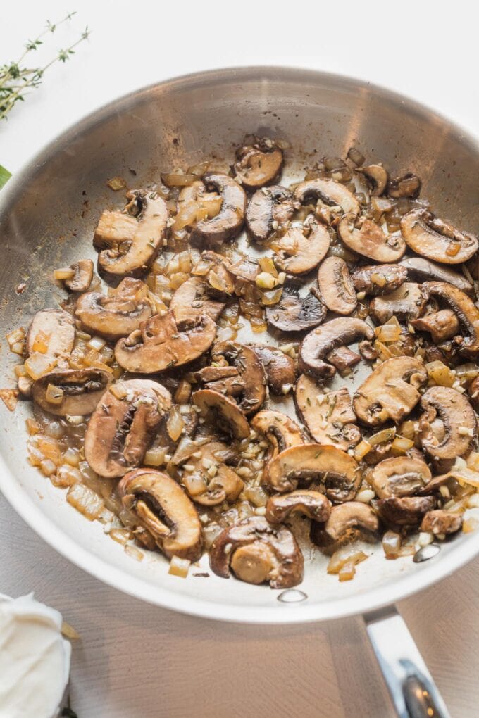 Onion and mushrooms sauteed together in a skillet.