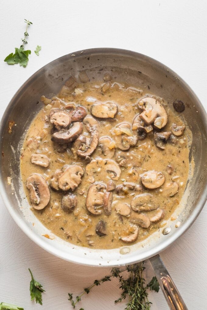 Broth mixed into mushrooms to begin forming a pan stroganoff sauce.
