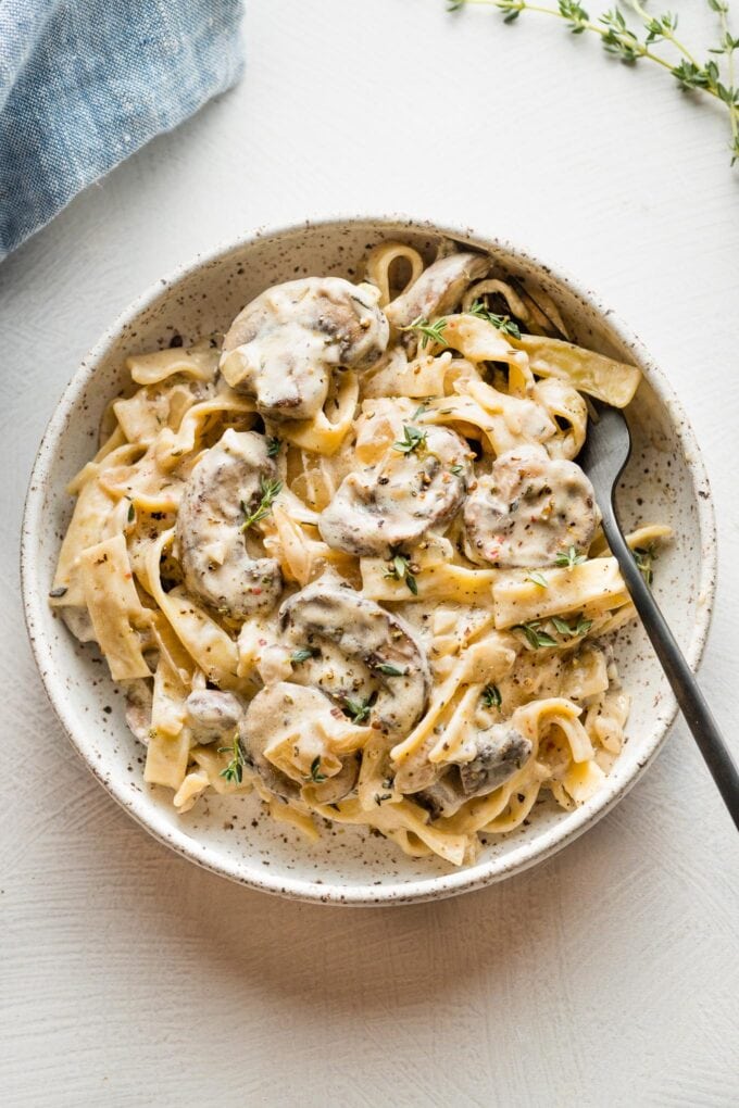 Small pasta bowl filled with a serving of creamy vegetarian mushroom Stroganoff, garnished with fresh thyme leaves.
