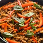 Close up of a Thai-inspired sweet basil chicken dish just cooked in a pan.