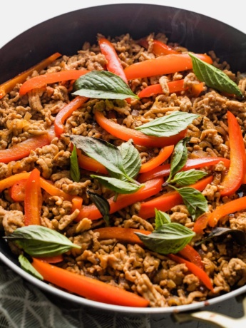 Close up of a Thai-inspired sweet basil chicken dish just cooked in a pan.
