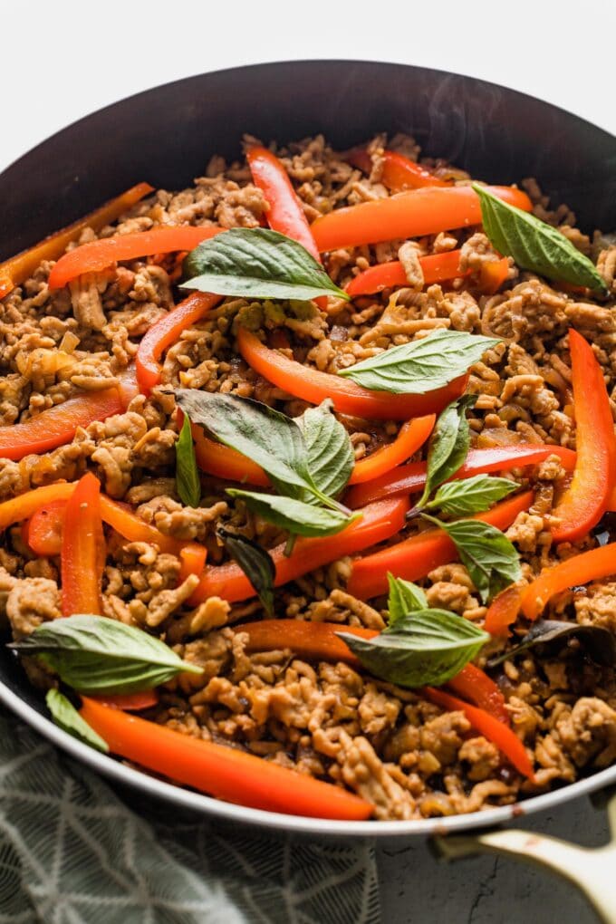 Close up of a Thai-inspired sweet basil chicken dish just cooked in a pan.