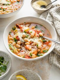 Angled view of an Italian chickpea soup being served with Parmesan and fresh parsley.