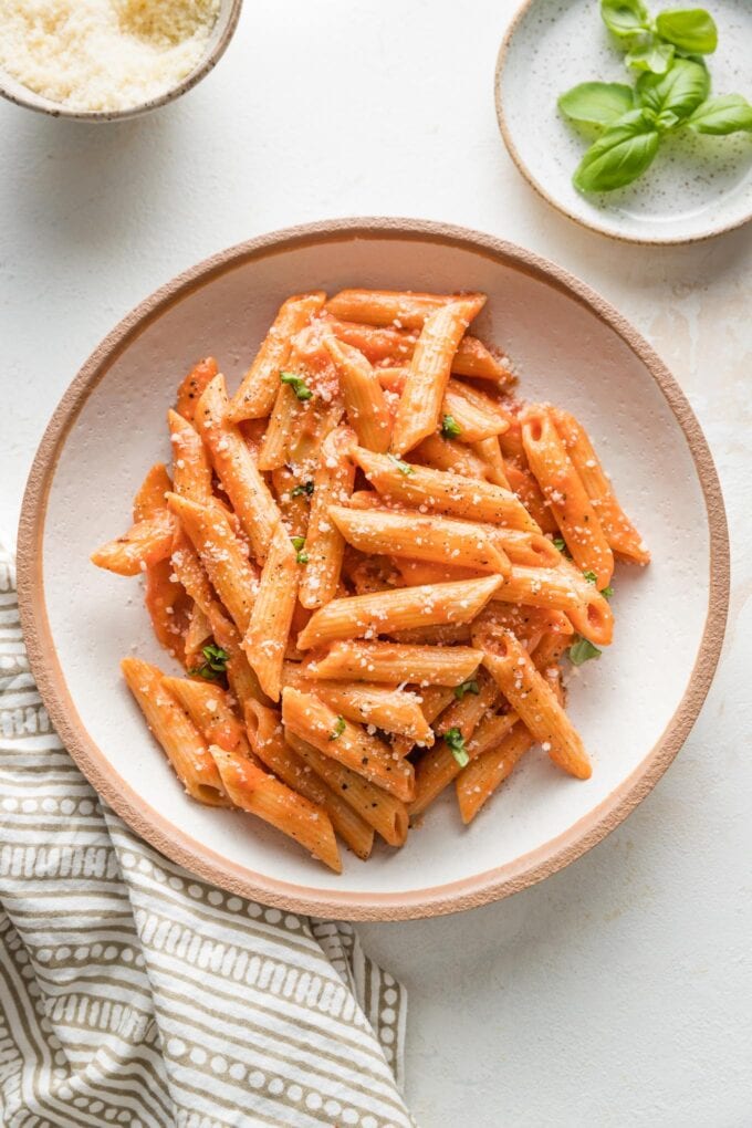 Bowl of creamy tomato pasta sprinkled with fresh grated Parmesan.