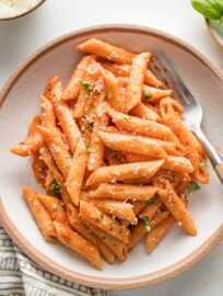 Bowl of creamy tomato pasta sprinkled with fresh grated Parmesan.