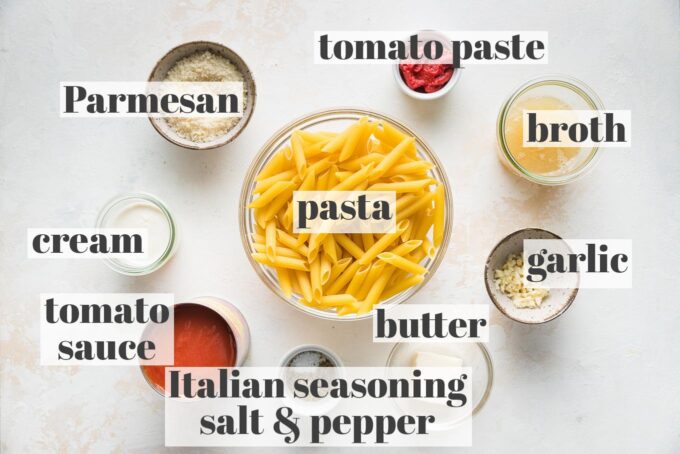 Labeled photo of pasta, Parmesan, tomato sauce and paste, garlic, broth, cream, and Italian seasoning measured into prep bowls.