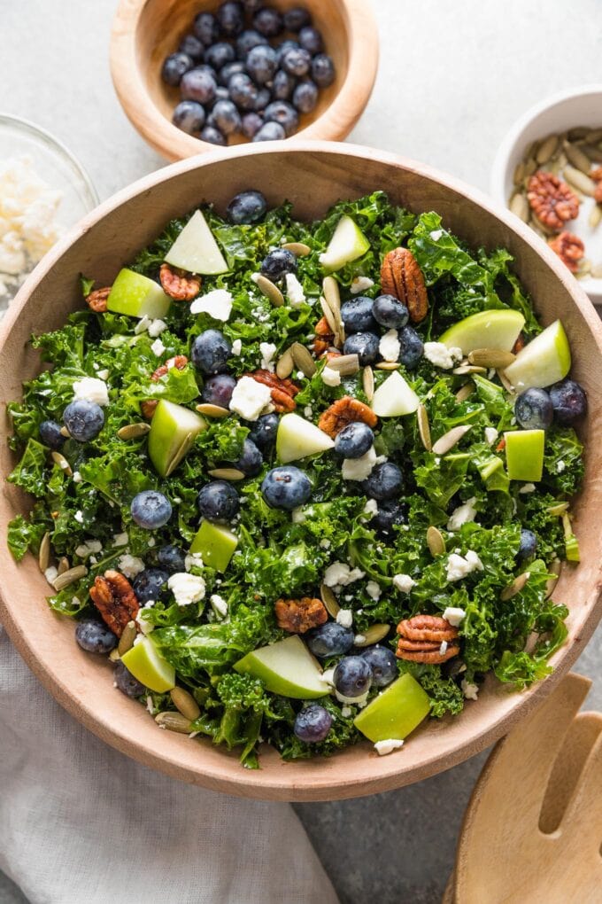 Kale blueberry salad tossed together and transferred into a wooden serving bowl.