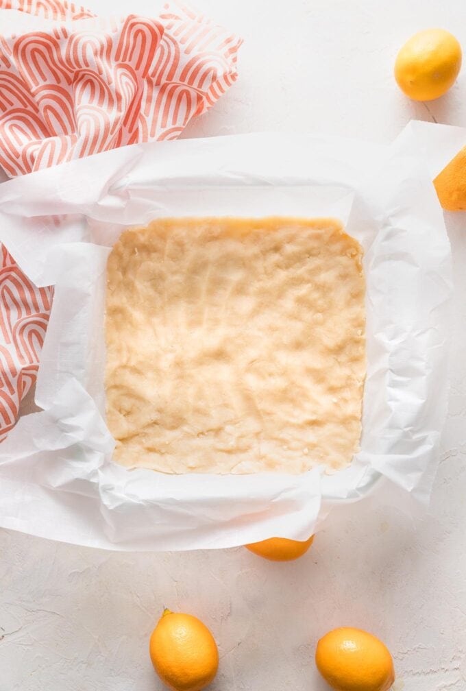 Shortbread crust pressed into a parchment-lined baking pan.