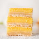 Close-up of three stacked Meyer lemon bars with shortbread crust.