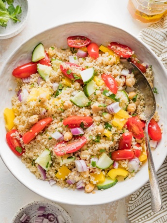 Bowl full of quinoa chickpea salad with tomatoes, cucumber, and a lemon dressing.