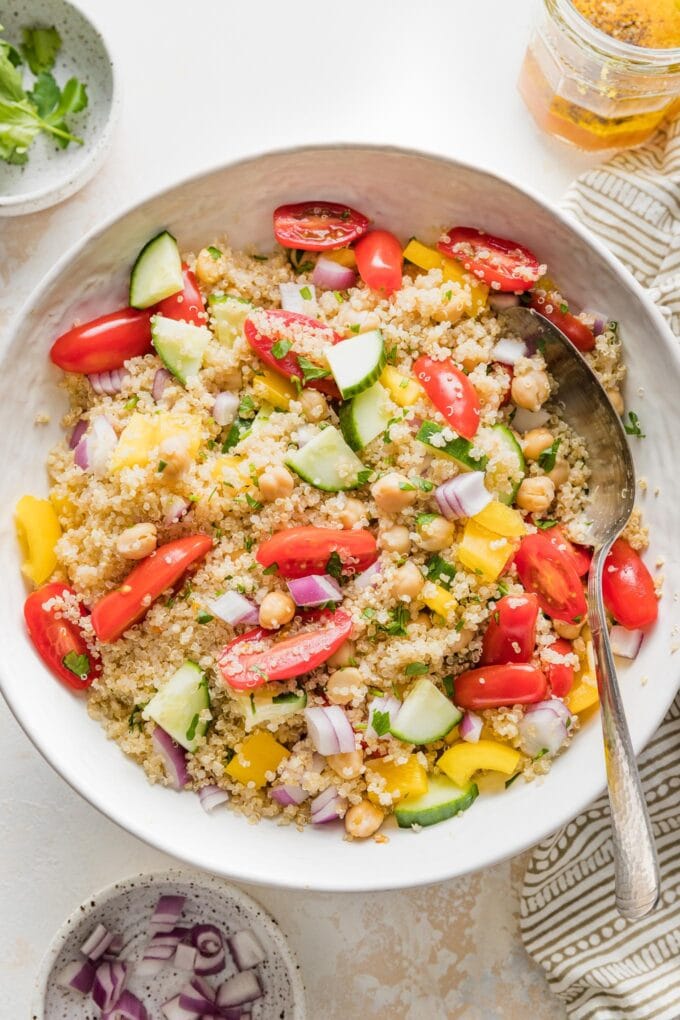 Bowl full of quinoa chickpea salad with tomatoes, cucumber, and a lemon dressing.