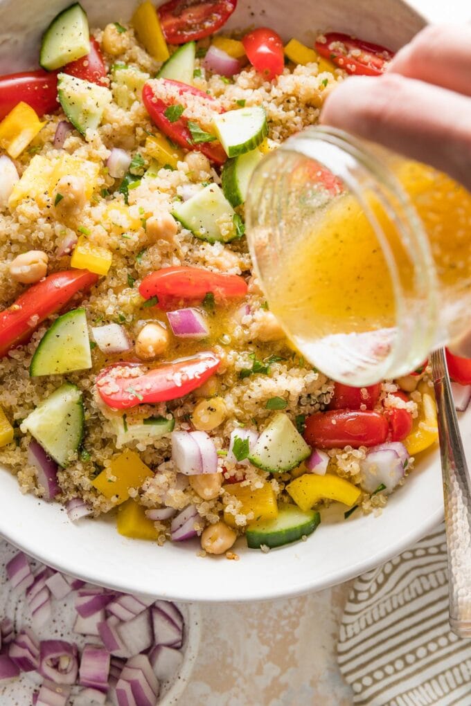 Close up of a homemade lemon dressing being poured over a quinoa chickpea salad.