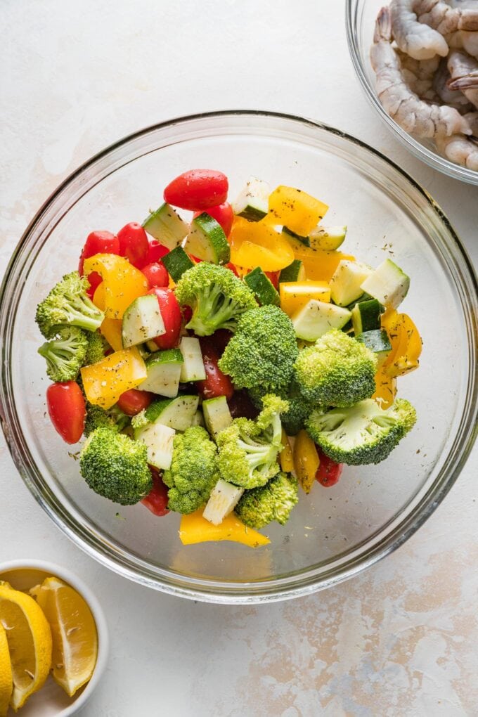 Prep bowl filled with broccoli, yellow bell pepper, cherry tomatoes, and zucchini, all chopped into bite-sized pieces.