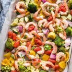 Sheet pan filled with oven-roasted shrimp and vegetables seasoned with garlic, Italian herbs, and a squeeze of lemon.