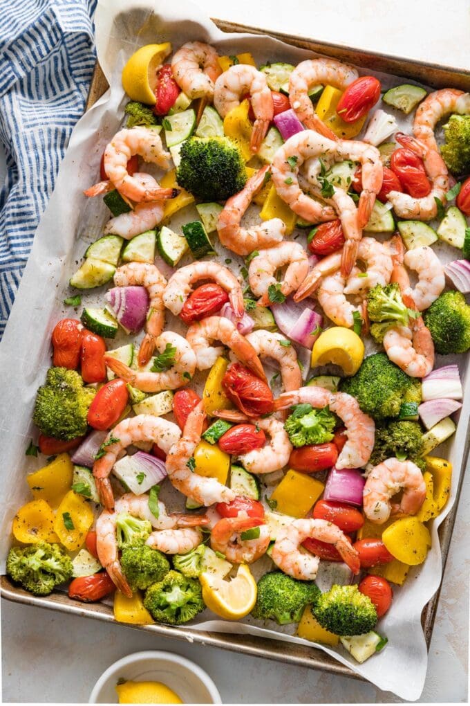 Sheet pan filled with oven-roasted shrimp and vegetables seasoned with garlic, Italian herbs, and a squeeze of lemon.