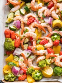 Close-up overhead image of sheet pan shrimp and veggies seasoned with garlic and Italian seasoning.