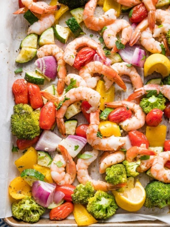 Close-up overhead image of sheet pan shrimp and veggies seasoned with garlic and Italian seasoning.