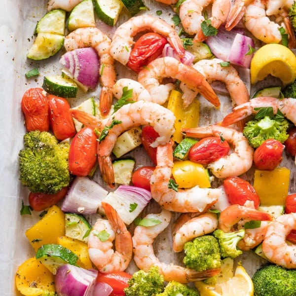 Close-up overhead image of sheet pan shrimp and veggies seasoned with garlic and Italian seasoning.