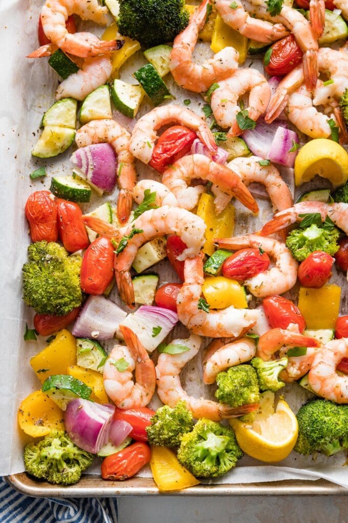 Close-up overhead image of sheet pan shrimp and veggies seasoned with garlic and Italian seasoning.