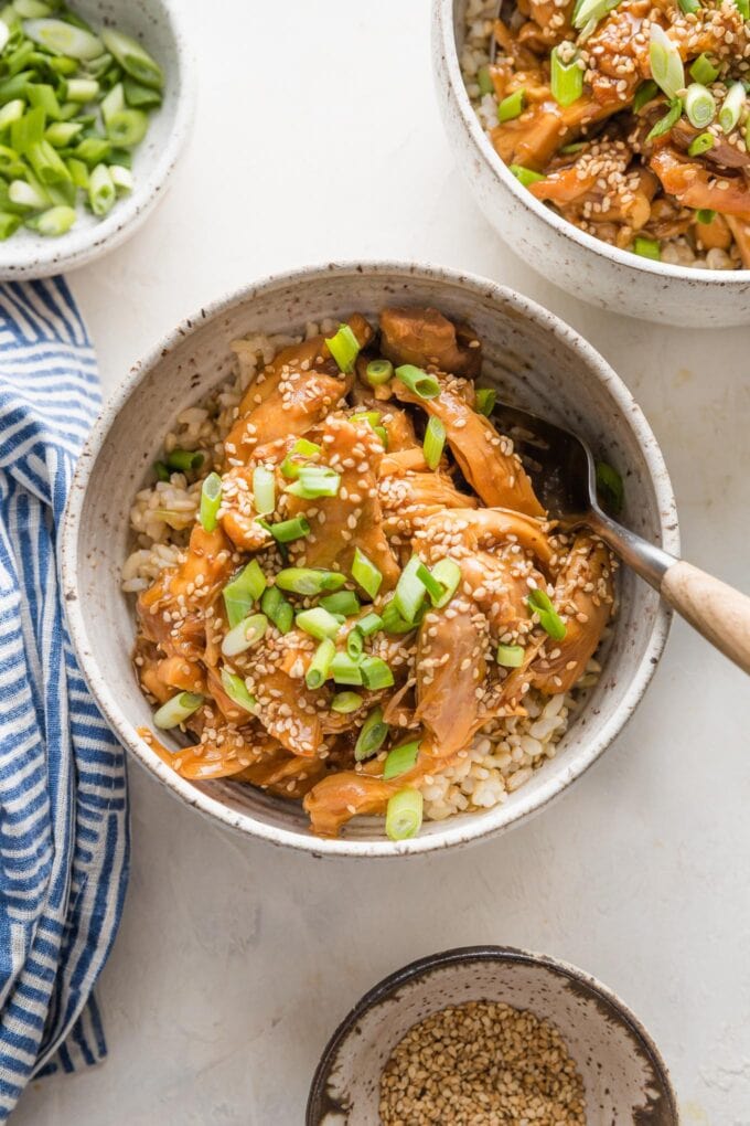 Two bowls of slow cooker teriyaki chicken ready to eat with forks.
