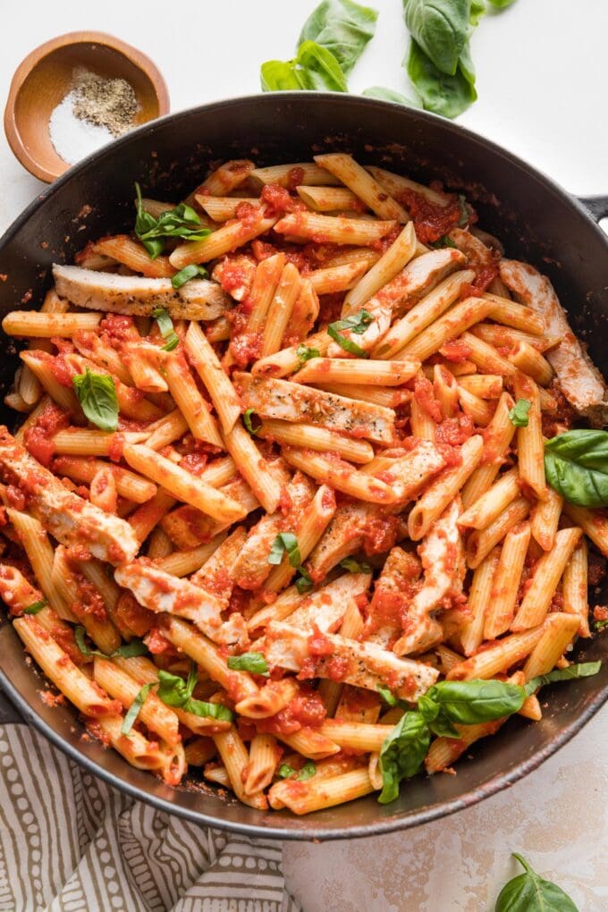 Cast iron skillet filled with chicken marinara pasta ready to serve.