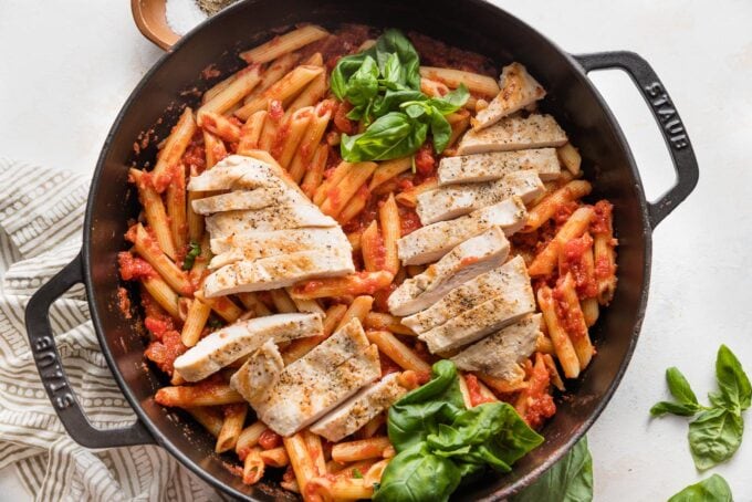 Chicken breasts sliced into strips and added to a skillet with pasta marinara.