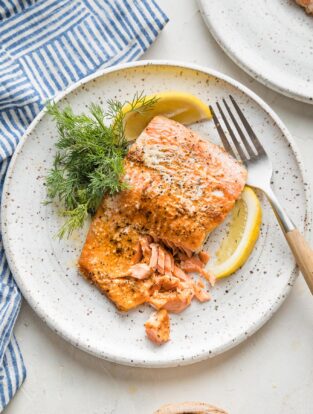 Flaky salmon plated with a lemon wedge and fresh dill.