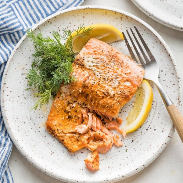 Flaky salmon plated with a lemon wedge and fresh dill.