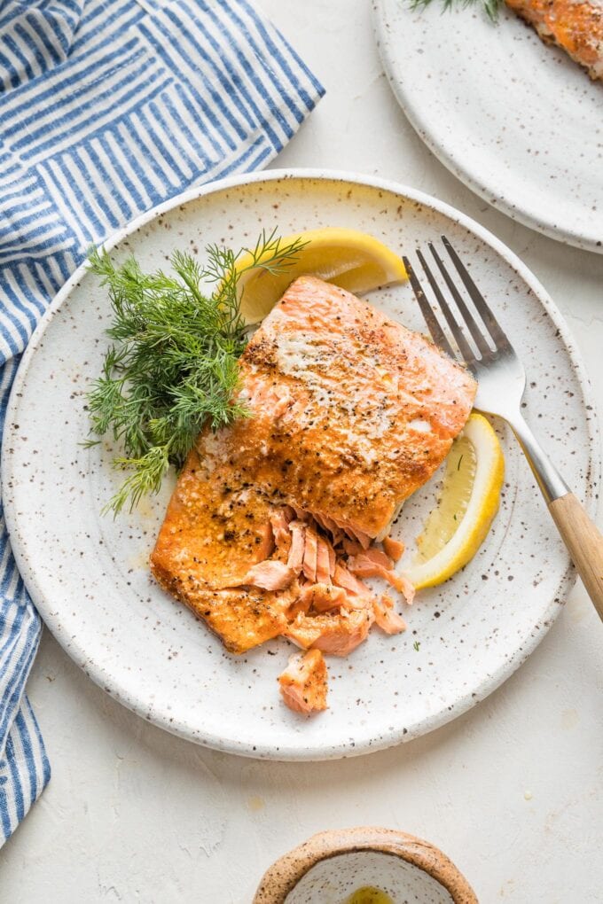 Flaky salmon plated with a lemon wedge and fresh dill.