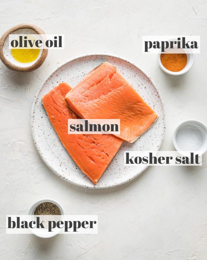 Labeled photo of salmon filets, olive oil, kosher salt, black pepper, and paprika in prep bowls.