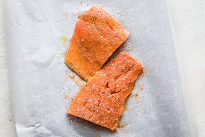 Uncooked salmon fillets on parchment paper.