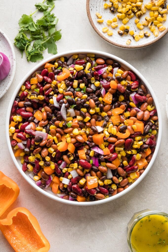 A large Mexican three bean salad with homemade cilantro vinaigrette, in a white bowl ready to serve.