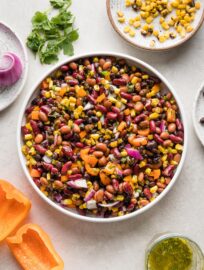 A large Mexican three bean salad with homemade cilantro vinaigrette, in a white bowl ready to serve.