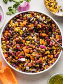 A large Mexican three bean salad with homemade cilantro vinaigrette, in a white bowl ready to serve.