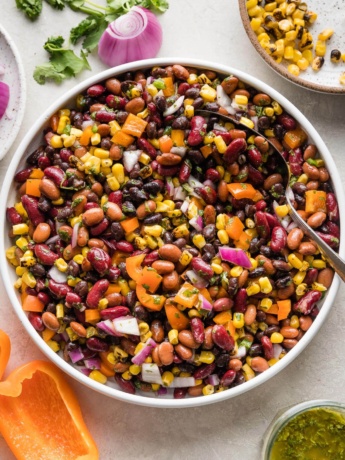 A large Mexican three bean salad with homemade cilantro vinaigrette, in a white bowl ready to serve.